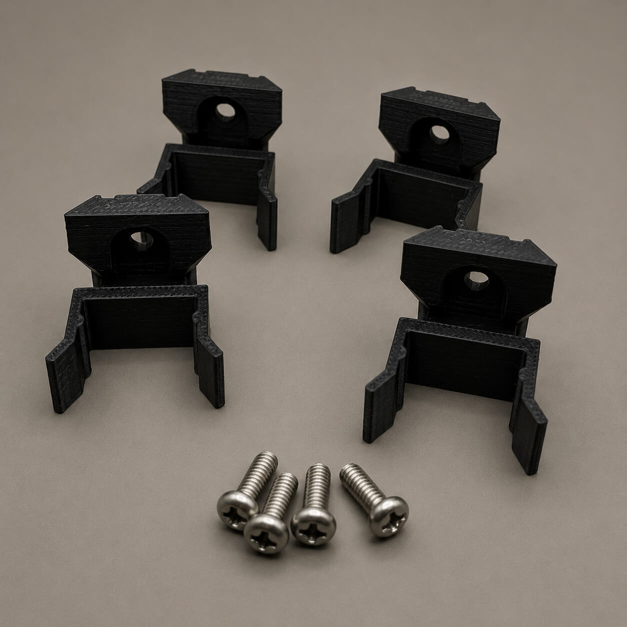 Black plastic brackets with screws on a beige background