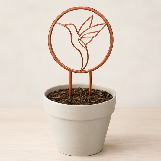 Decorative hummingbird plant trellis displayed in an indoor flowerpot