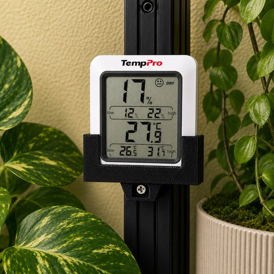Digital thermometer with humidity and temperature readings in front of green plants