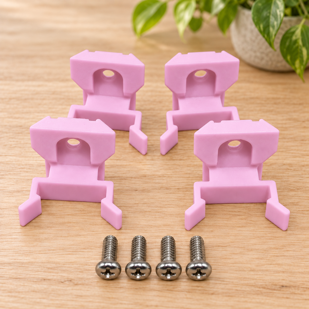 Four pink Vivosun T5 vertical mounting clips for IKEA Milsbo with stainless steel screws on a wooden tabletop beside a plant.