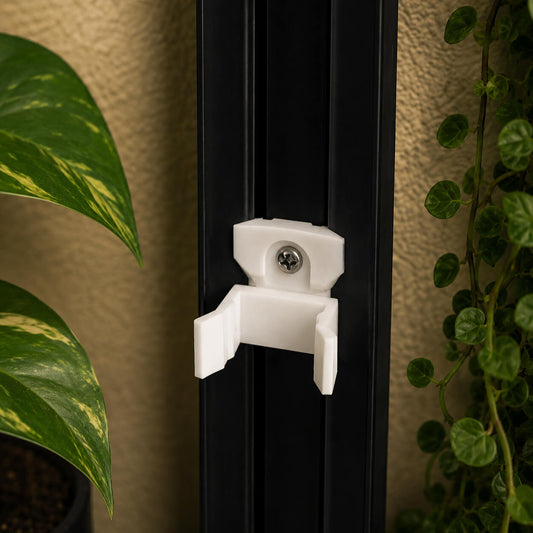 White bracket attached to a black door with plants in the background