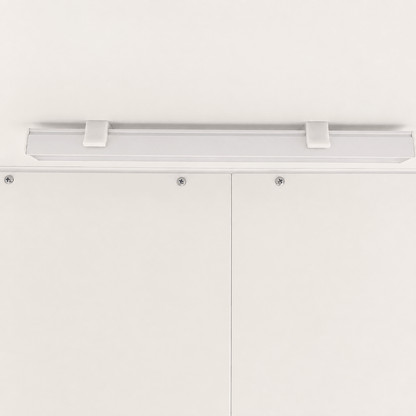 A modern linear LED light fixture with a matte white finish, mounted horizontally on a white ceiling above white cabinet doors.