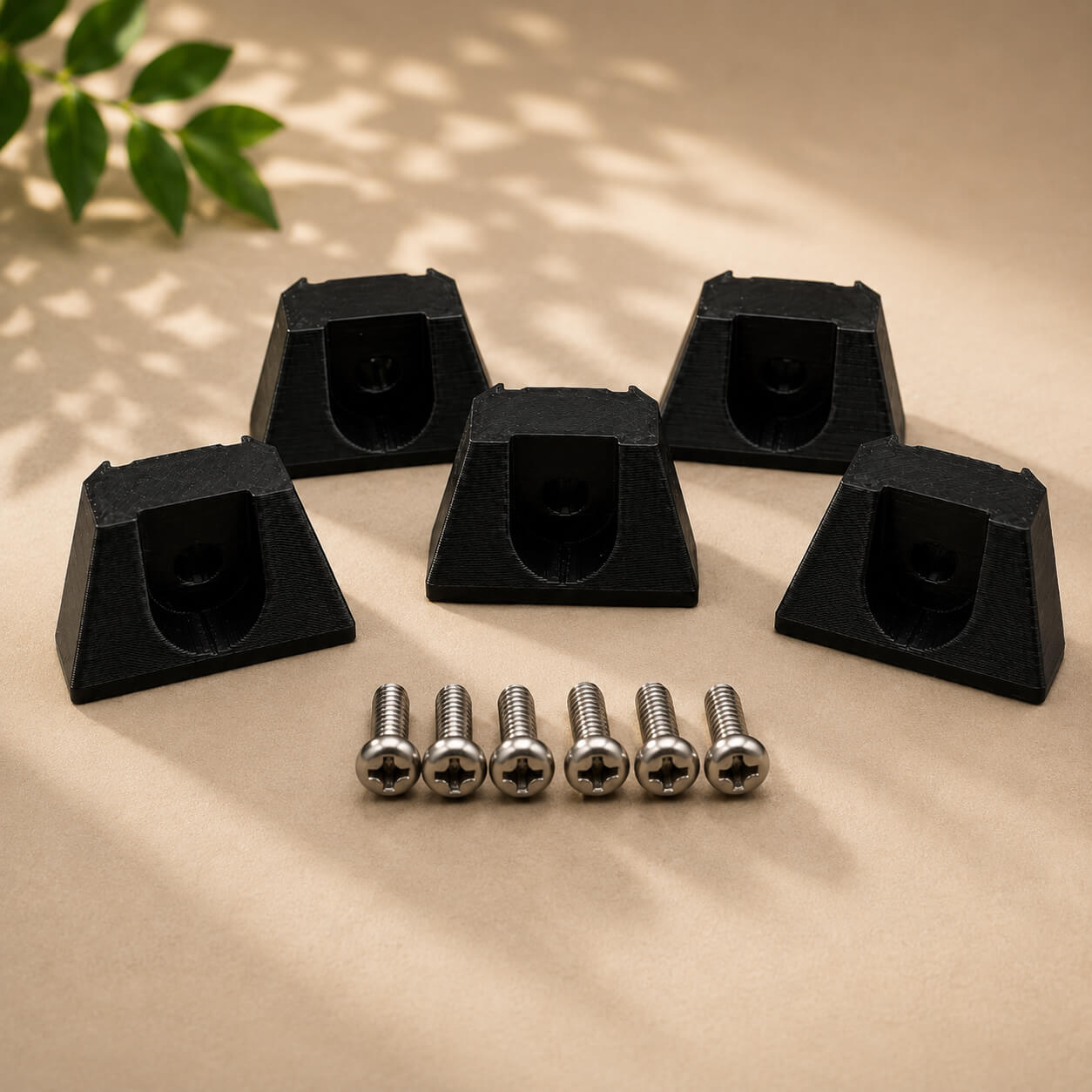 Set of black plastic furniture glides and screws on a beige surface with a plant in the corner.
