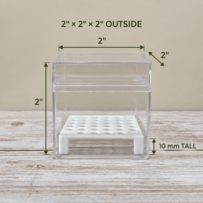 A clear acrylic storage box with a white perforated base, shown on a wooden surface with dimension labels indicating 2 x 2 x 2 inches outside and 10 mm tall.
