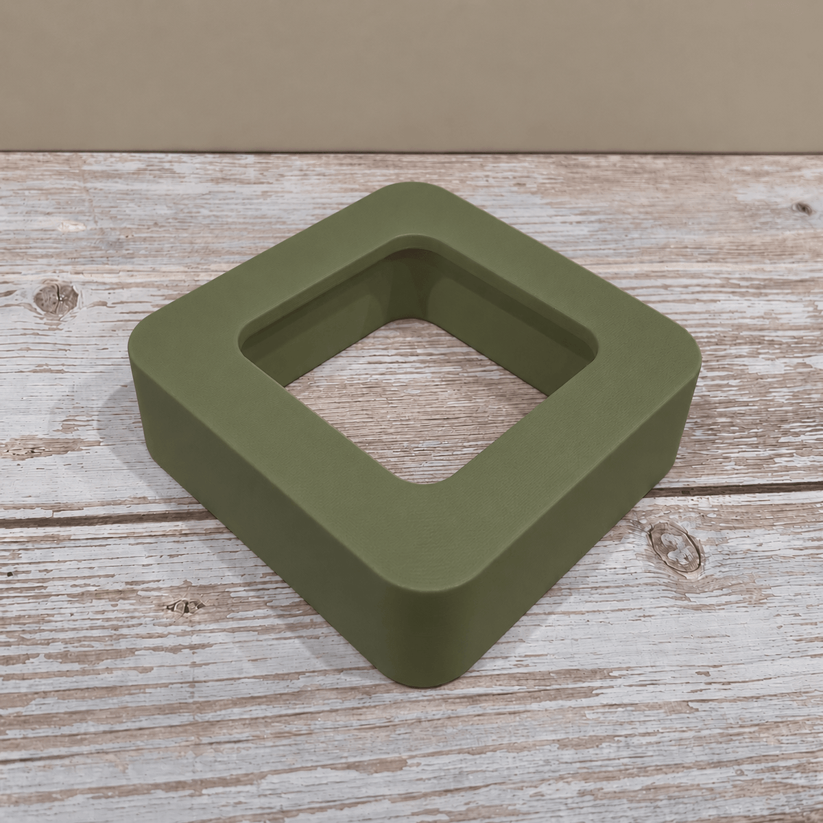 Olive green Govee H5179 magnetic hygrometer mount shown without the sensor on a light wooden tabletop.