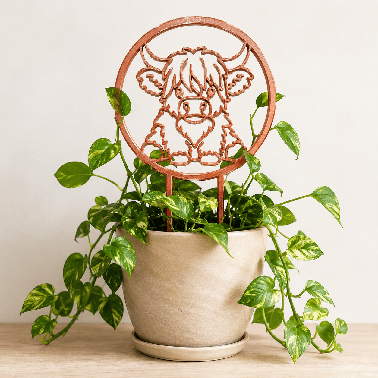 Highland cow trellis supporting climbing vines in a ceramic planter