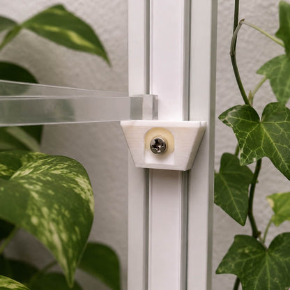 Close-up of a shower door handle with green plants in the background