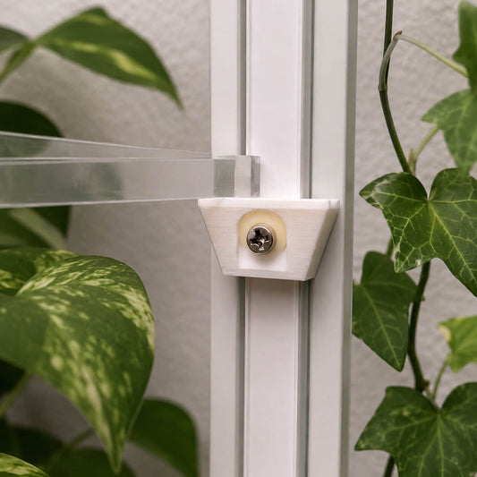 Close-up of a shower door handle with green plants in the background
