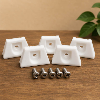 White plastic corner brackets with screws on a wooden surface with a plant in the background