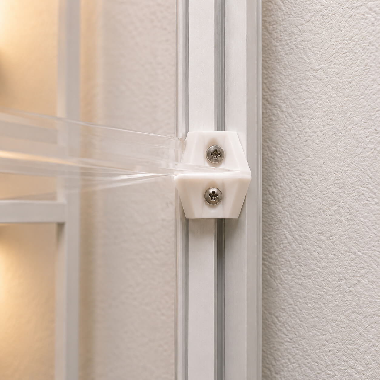 Close-up of a white cabinet with a clear plastic strip and metal bracket.