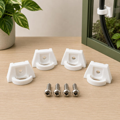White corner brackets and screws on a wooden surface with a plant in the background