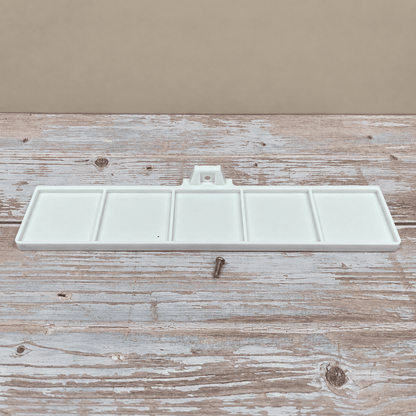 A white plastic multi-compartment paint palette tray with a small metal screw, displayed on a rustic, weathered wooden surface against a solid beige background.