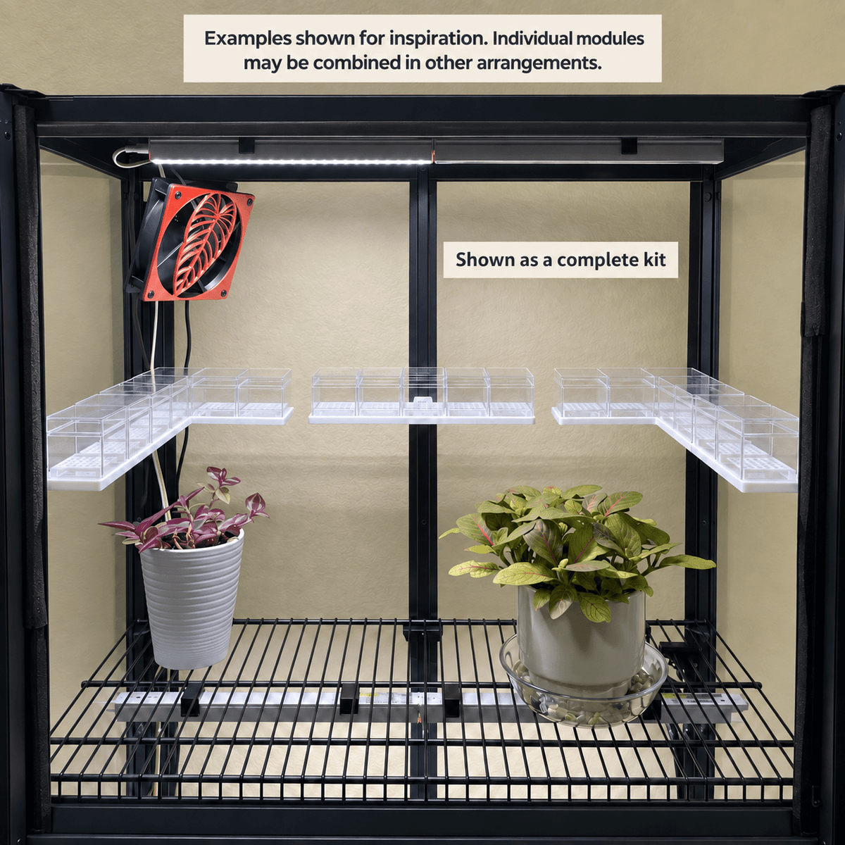 Black metal grow light stand with two shelves, clear plastic tray modules, and an integrated light bar, shown with two potted plants and a hanging fan accessory. Text labels note that the modules may be combined in other arrangements and that it is shown as a complete kit.