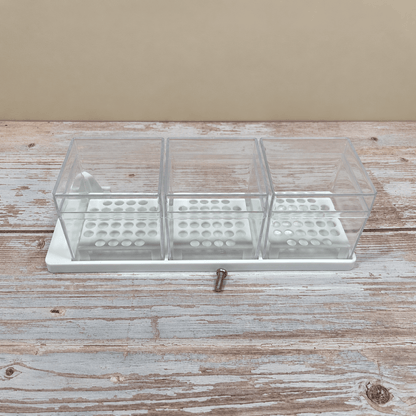 Three clear plastic drawer organizer boxes with white bases and a small silver screw, shown on a rustic whitewashed wooden surface against a beige wall.