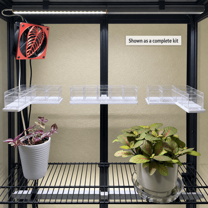 Black metal indoor plant grower's rack with two shelves, clear plastic grow trays, a red fan, and two potted plants, shown as a complete kit against a beige wall.