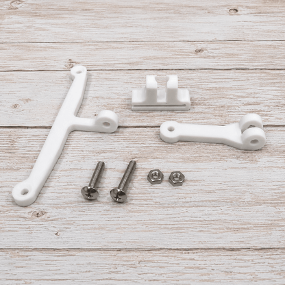 White plastic mounting brackets and silver metal screws and washers laid out on a light wood plank surface.