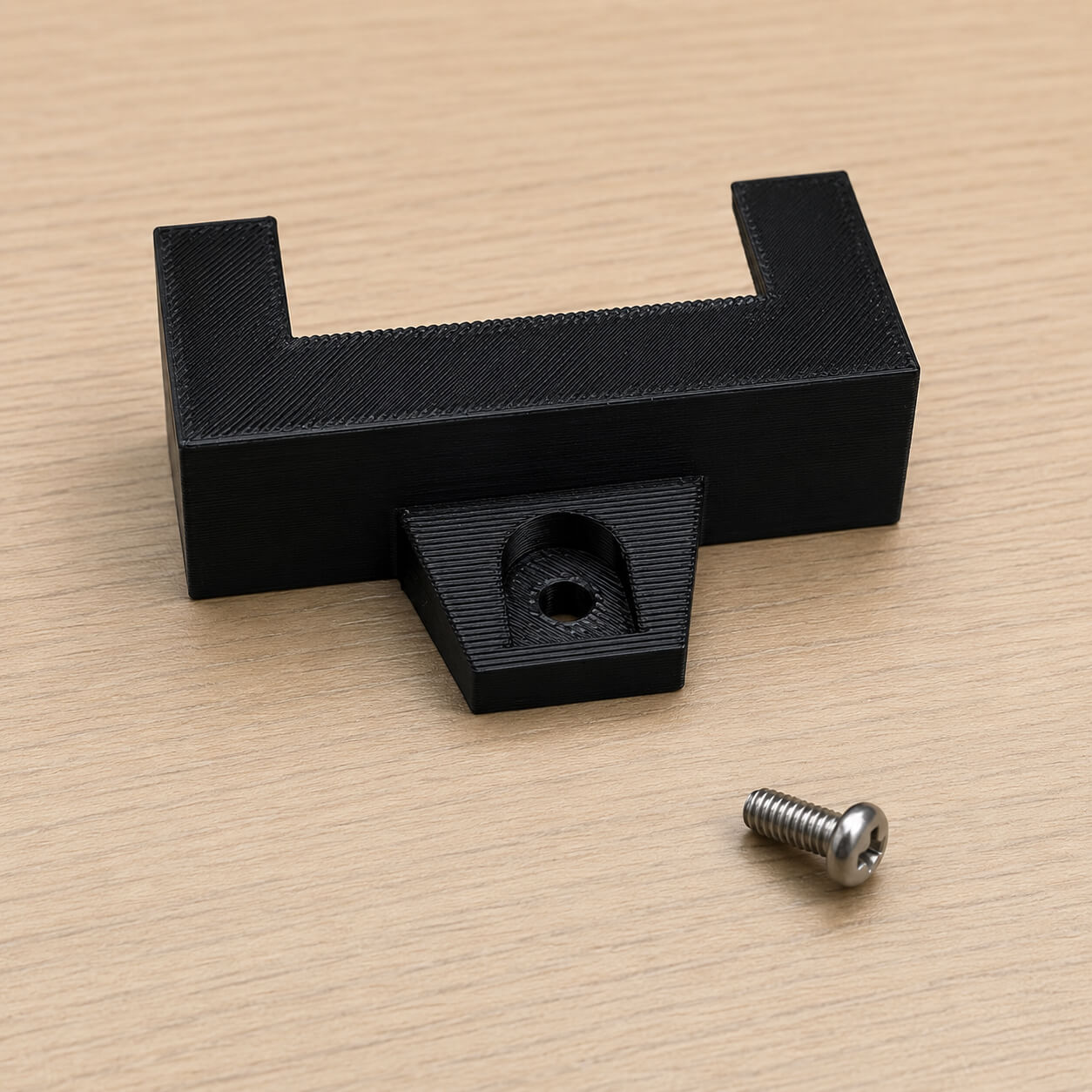 Black metal bracket with a screw on a beige surface