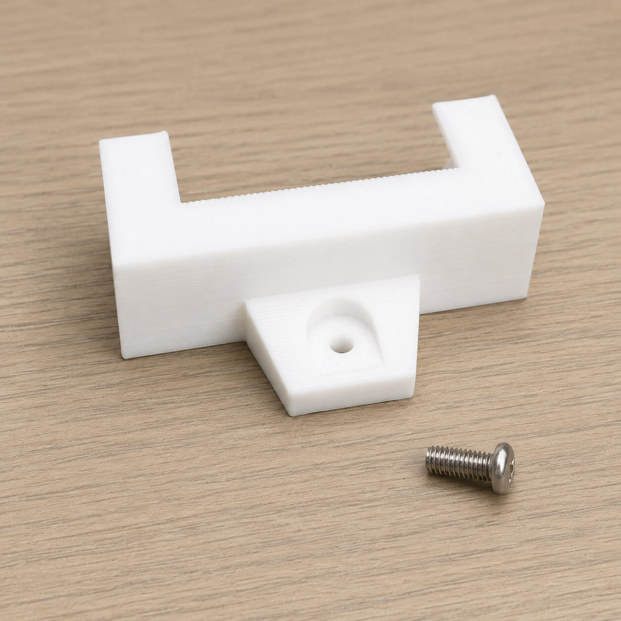 White plastic bracket with a screw on a wooden surface