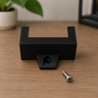 Black metal bracket with a screw on a wooden surface
