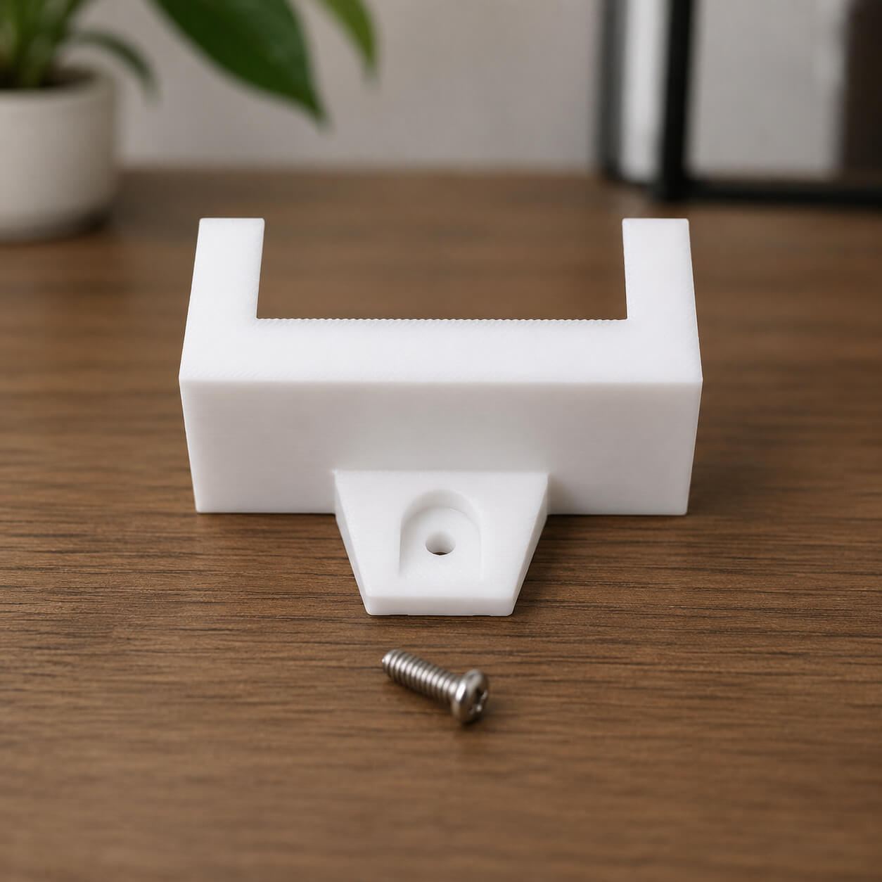 White plastic bracket with a screw on a wooden surface
