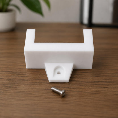 White plastic bracket with a screw on a wooden surface