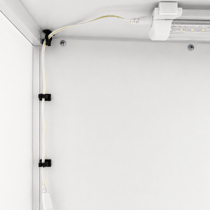 Black cable management clips holding a white power cord along a white metal track, shown in a clean, industrial setting.