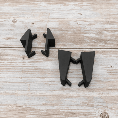 Three matte black geometric drawer pull knobs arranged on a light weathered wood surface.