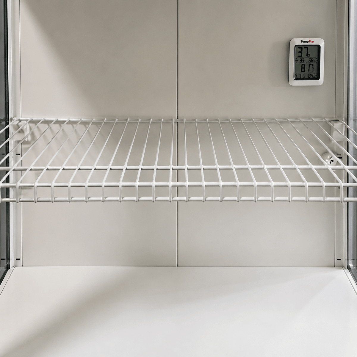 White wire storage shelf inside a refrigerator or freezer compartment, with a digital temperature display mounted on the back wall.