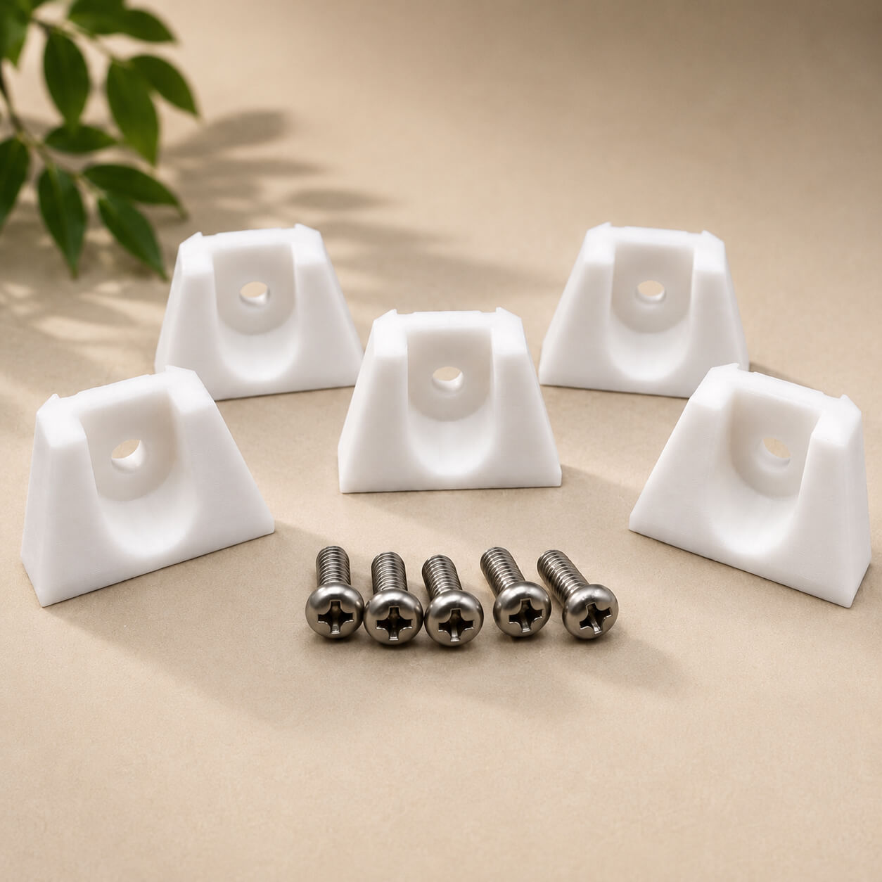 White triangular corner protectors with screws on a beige surface with a plant in the background