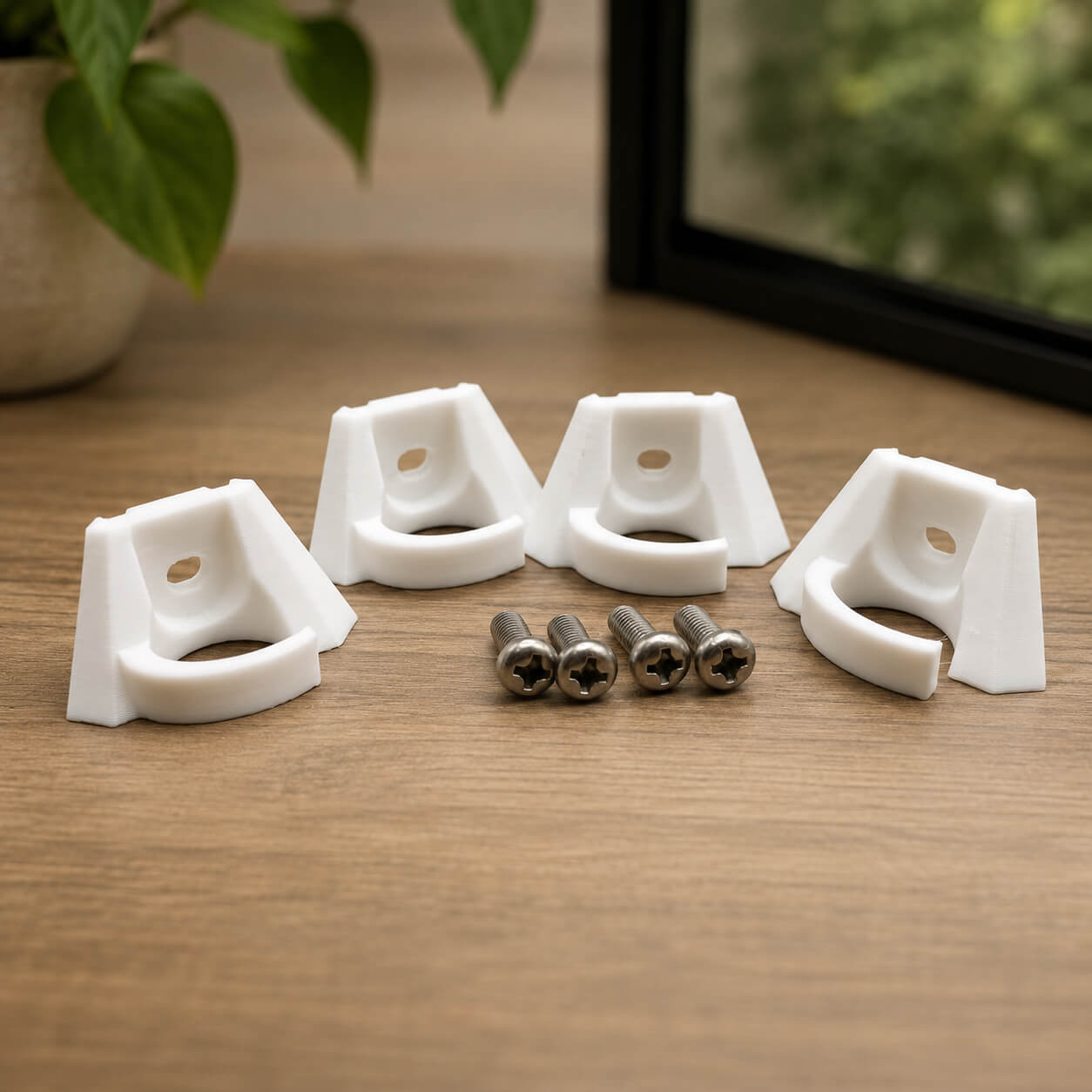 Four white corner brackets with screws on a wooden surface