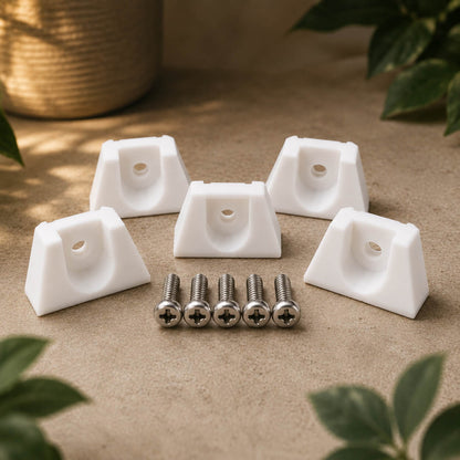 White corner brackets with screws on a beige surface with green leaves around