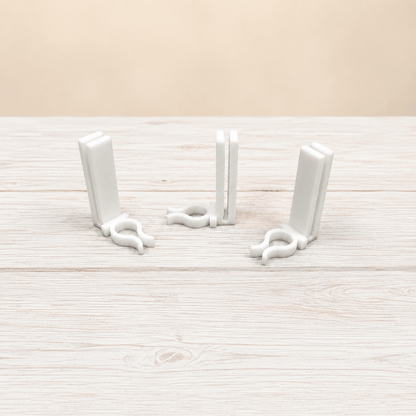 Three white plastic bookends arranged on a light wood-grained surface against a beige background.